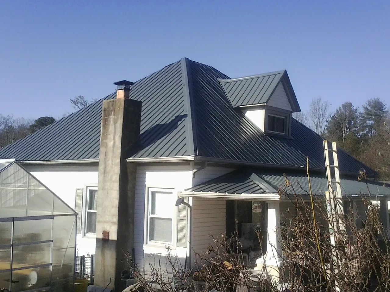 Dark blue standing seam metal roof on a white farmhouse with dormer — Slate & Tile Roof Repair by Roofing Brothers in Fort Montgomery