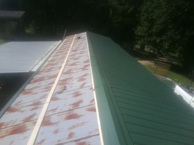 Old rusted panels beside newly installed green metal roofing — Wind Damage Roof Repair by Roofing Brothers in Fort Montgomery