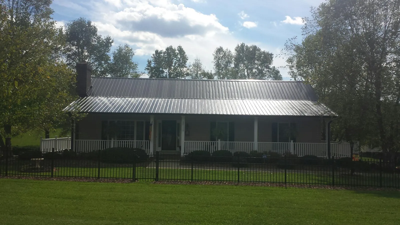 Gray metal roof on a brick ranch with a full width front porch — Gutter Guard Installation work by our crew in Fort Montgomery