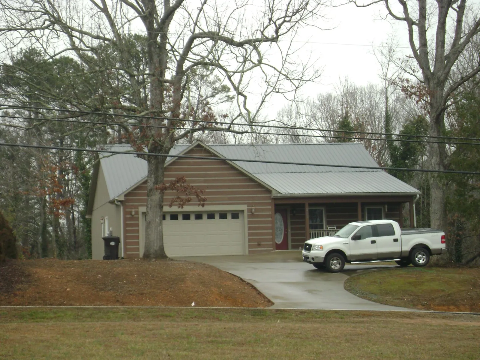 Gray metal roof on a log sided house with an attached two car garage in Fort Montgomery