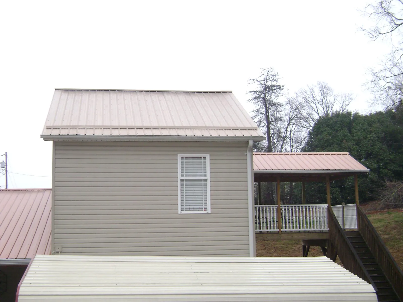 Tan metal roofs on a two story addition and attached porch, from a Roof Replacement job in Fort Montgomery